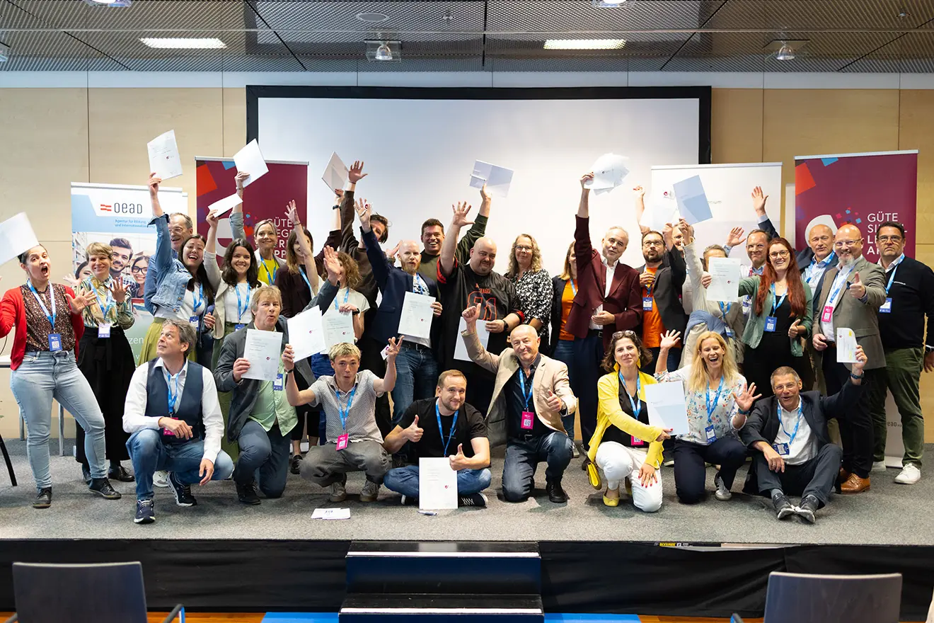 Gemeinsam für exzellente digitale Bildung Ein Gruppenfoto zahlreicher Preisträger auf einer Bühne, die stolz ihre Zertifikate für das Gütesiegel Lern-Apps 2025 in die Kamera halten.