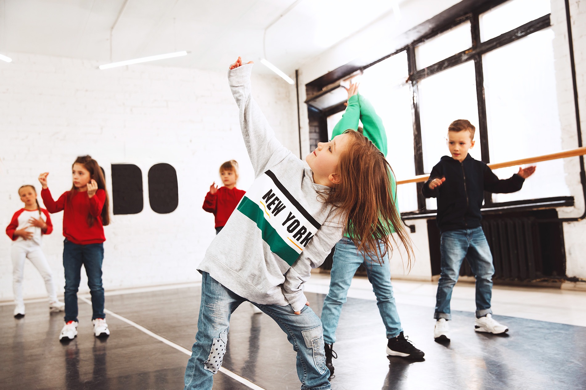 Ein Kind in einer kreativen Tanzpose im Tanzstudio – Zusammenhang zwischen kreativer Praxis und Gehirngesundheit.