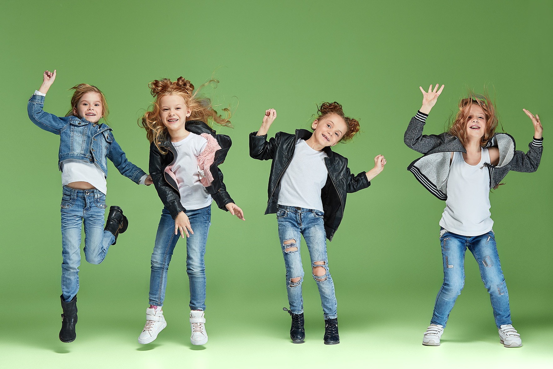 Praxisbeispiel: So motivierend ist Tanz im Sportunterricht Vier begeisterte Kinder springen und tanzen voller Energie vor einem grünen Hintergrund – moderne Umsetzung von Tanz im Unterricht.
