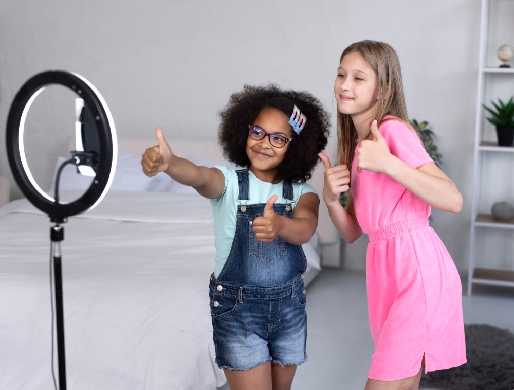 Digitale Tanzgrüße mit groove2grow Zwei Mädchen geben Daumen hoch vor einem Ringlicht und Smartphone – Produktion eines digitalen Tanzvideos.